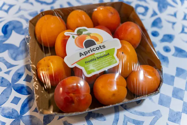 Dekoratif mavi ve beyaz masa örtüsü üzerinde paketlenmiş taze kayısılar.