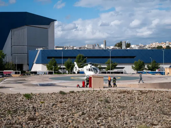 Helikopter mavi binanın dışındaki helikopter pistinde, işçilerle birlikte.