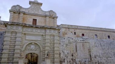 Mdina, Malta 'nın görkemli barok giriş kapısı, süslü taş tasarımı ve güçlendirilmiş duvarlarıyla. Geçit, tarihi Sessiz Şehir 'e ikonik giriş noktası olarak hizmet veriyor..