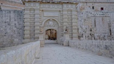 Mdina, Malta 'nın görkemli barok giriş kapısı, süslü taş tasarımı ve güçlendirilmiş duvarlarıyla. Geçit, tarihi Sessiz Şehir 'e ikonik giriş noktası olarak hizmet veriyor..