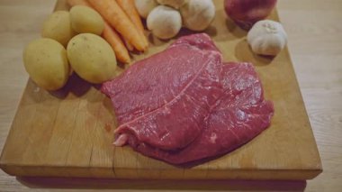 Tahtada taze havuçlu, mantarlı, patatesli ve sarımsaklı çiğ biftek.