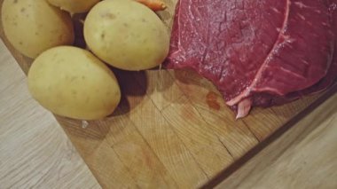 Tahtada taze havuç, mantar, patates, soğan ve sarımsaklı çiğ biftek.