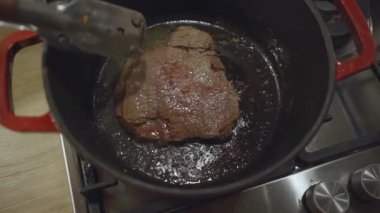 Fırının üzerinde kırmızı bir Hollanda fırınının içinde yağda kızartılan çiğ biftek.