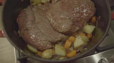Bifteği sebzeyle pişirmek kırmızı dökme demir tavada pişirmek.