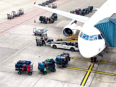 Zürih, İsviçre 06102024: İsviçre uçağına yükleme Uluslararası Havalimanı kapısına yanaştı. Bagaj vagonu uçağın önüne.