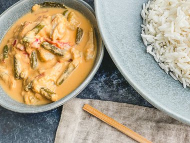 Kırmızı Tayland usulü körili tavuk. Tabakta sos. pirinç ayrı tabakta pastel mavi tabakta, yemek çubukları peçete yüksek açılı, kapat.