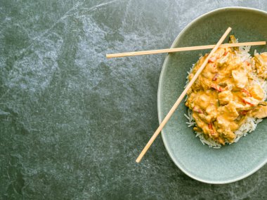 Kırmızı Tayland usulü körili tavuk, pastel yeşil tabakta pirinç, mermer taşlı yemek çubukları, yukarıdan aşağıya görüş, kapat, boşluğu kopyala