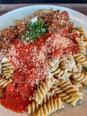 domates soslu makarna ve bolonez, parmesan peyniri ve beyaz tabakta garnitür, dikey çekim, kapat.