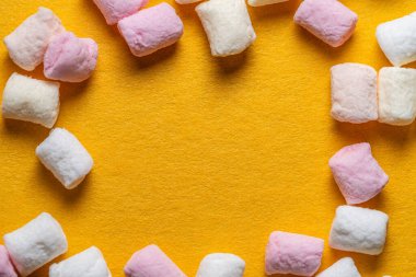 Güneş sarısı turuncu zemin üzerinde kenarlık çerçeve olarak pastel renkte renkli marşmelov parçaları, tam çerçeve, boşluk kopyala