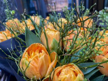turuncu renkli lale buketleri ve yeşil dolgulu siyah kağıt ambalajlar satışa hazır.