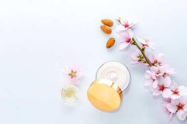 Kavanozda desenli cilt kremi, yağ, beyaz arka planda badem çiçeğinin kapağında yansıma, kozmetik konsept, yukarıdan aşağıya görünüm, kapat, boşluğu kopyala