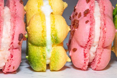 Renkli Fransız badem kurabiyesi ya da taze pembe ve sarı, yatay sıra, kafa kafaya, makro, kapat.