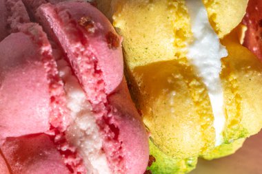 Pembe ve sarı Fransız badem kurabiyesi ya da güneş ışığında kurabiyeler, krema dolgusunun üstüne. Taze pembe ve sarı renkler, üstten aşağı, makro, kapat, tam kare