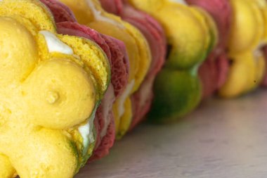 Kavisli sıra halinde Fransız bademli kurabiyeleri. parlak çilek pembesi ve sarı yeşil limon, kafa kafaya, kapalı, kopyalama alanı
