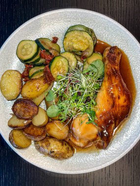 Kabaklı fırında patates püresi, soslu kızarmış tavuk budu, siyah tabakta garnitür, üstten aşağı görüş, dikey çekim