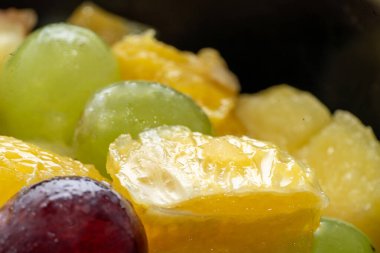 Meyve parçaları. Su damlaları ve portakallı kırmızı üzüm, siyah üzerine taze meyve salatası, kopyalama alanı, kapat