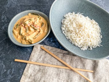 Kırmızı Tayland usulü körili tavuk. Tabakta sos. pirinç ayrı tabakta pastel mavi tabakta, yemek çubukları peçete yüksek açılı, kapat.