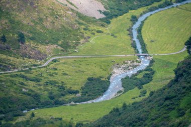 Kavşağı geçen buz mavisi bir buzul deresi. Yaz havası manzaralı yeşil vadi manzarası