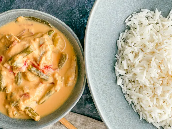 Kırmızı Tayland usulü körili tavuk. Tabakta sos. pirinç ayrı tabakta pastel mavi tabakta, yemek çubukları peçete yüksek açılı, kapat.