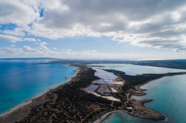 Tuz düzlükleri ve deniz ile göl arasında bir ada bulutlu bir gökyüzü, hepsi bir dron manzaralı.