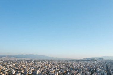 Atina 'nın panoramik manzarası, berrak bir gökyüzünün altındaki dağ zeminine uzanan uçsuz bucaksız şehir manzarasını sergiliyor.