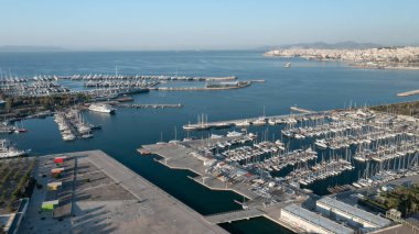 Parlak bir günde Marina Delta Kallithea 'nın sersemletici hava manzarası, botlarla dolu geniş marinayı, Akdeniz' in berrak mavi sularını ve genişleyen kentsel manzarayı gözler önüne seriyor.