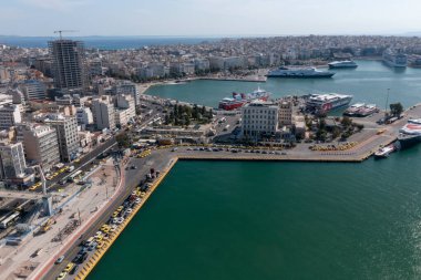 Pire Limanı, Atina, Yunanistan 'ın hava manzarasında limana yanaşan canlı feribot terminalleri ve büyük gemiler görülüyor. Caddelerde ve caddelerde dolup taşan taksilerle dolu bir sahil kenarı görüntüsü var.
