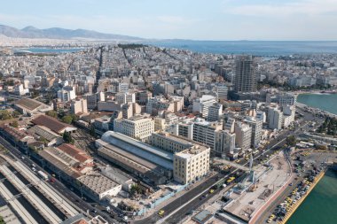 Atina, Yunanistan yakınlarındaki Pire Tren İstasyonu ve çevresindeki kıyı kentinin etkileyici bir hava manzarası. Fotoğraf, modern ve tarihi karışımıyla hareketli şehir manzarasını yakalıyor.