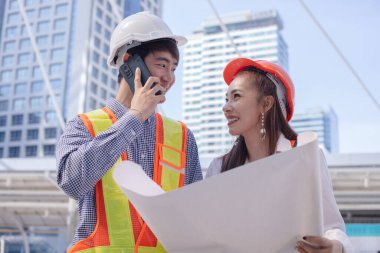 Profesyonel iki mühendis planı tartışıyor ve tutuyor..