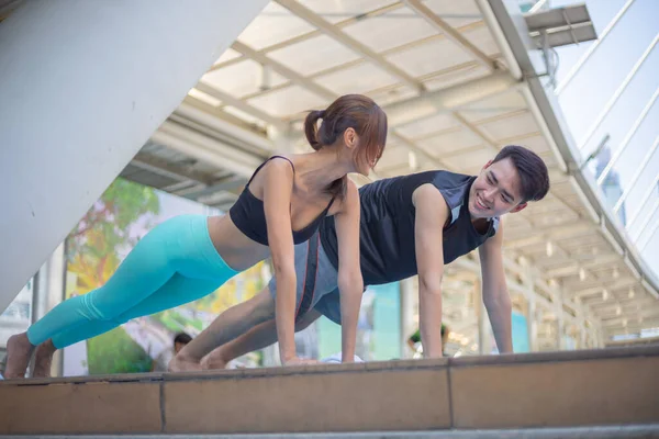 Formda bir adam ve güzel bir kadın şehirde yoga yapıyor..