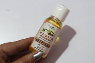 El ele tutuşan Jojoba yağı şişesi 