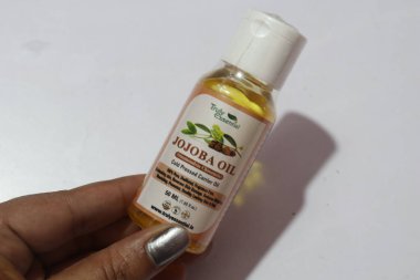 kadın elinde jojoba yağı şişesi