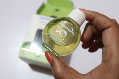 Kadın eli cam şişede yüz serumunu tutuyor. 