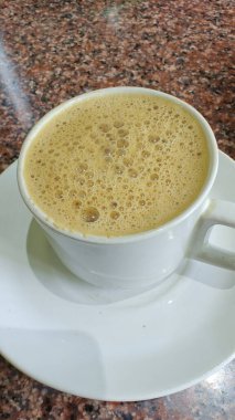 Masanın üzerinde bir fincan kapuçino.