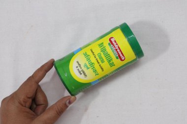 Elinde yeşil bir Hint ilacı paketi var.