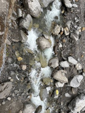 Dağlardaki kayalardan akan küçük akarsuyun manzarası.