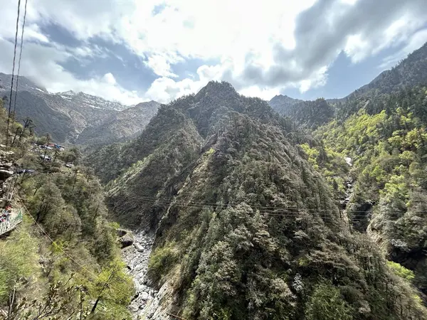 Parçalı bulutlu gökyüzünün altında yemyeşil bitki örtüsüyle kaplı dağların güzel manzarası.