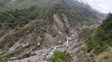 Yeşil dağlardaki kayalardan akan küçük akarsuyun manzarası.