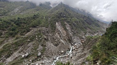 Yeşil dağlardaki kayalardan akan küçük akarsuyun manzarası.