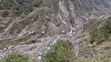Yeşil dağlardaki kayalardan akan küçük akarsuyun manzarası.