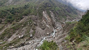 Yeşil dağlardaki kayalardan akan küçük akarsuyun manzarası.