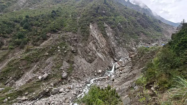 Yeşil dağlardaki kayalardan akan küçük akarsuyun manzarası.