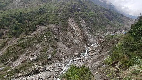 Yeşil dağlardaki kayalardan akan küçük akarsuyun manzarası.