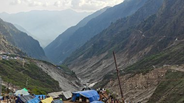 Yeşil çayırların güzel manzarası, mavi gökyüzü karlı dağlar, mağazalar, oteller ve Kedarnath Tapınağı Yolu 'na giden Shiva hayranlarından oluşan kalabalık.