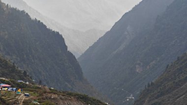 Yeşil çayırların güzel manzarası, mavi gökyüzü karlı dağlar, mağazalar, oteller ve Kedarnath Tapınağı Yolu 'na giden Shiva hayranlarından oluşan kalabalık.