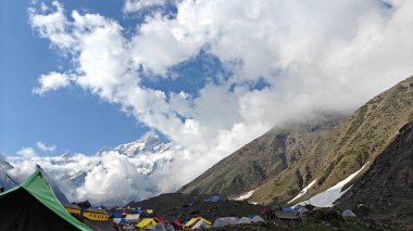 Yeşil çayırların güzel manzarası, mavi gökyüzü karlı dağlar, mağazalar, oteller ve Kedarnath Tapınağı Yolu 'na giden Shiva hayranlarından oluşan kalabalık.