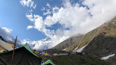 Yeşil çayırların güzel manzarası, mavi gökyüzü karlı dağlar, mağazalar, oteller ve Kedarnath Tapınağı Yolu 'na giden Shiva hayranlarından oluşan kalabalık.