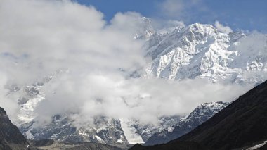 Karlı Himalaya dağları ve mavi gökyüzünde bulutlarla güzel bir manzara.