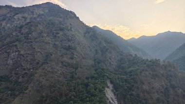 Himalaya dağlarında gün batımında yeşil ağaçlar yetişiyor.