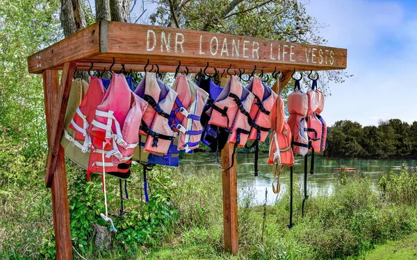 Loaner Life Vests:  A wooden rack holds life vests free to use for boaters on a river in Wisconsin.